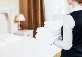 Hotel service. housekeeping maid with towels and bedclothes linen in room